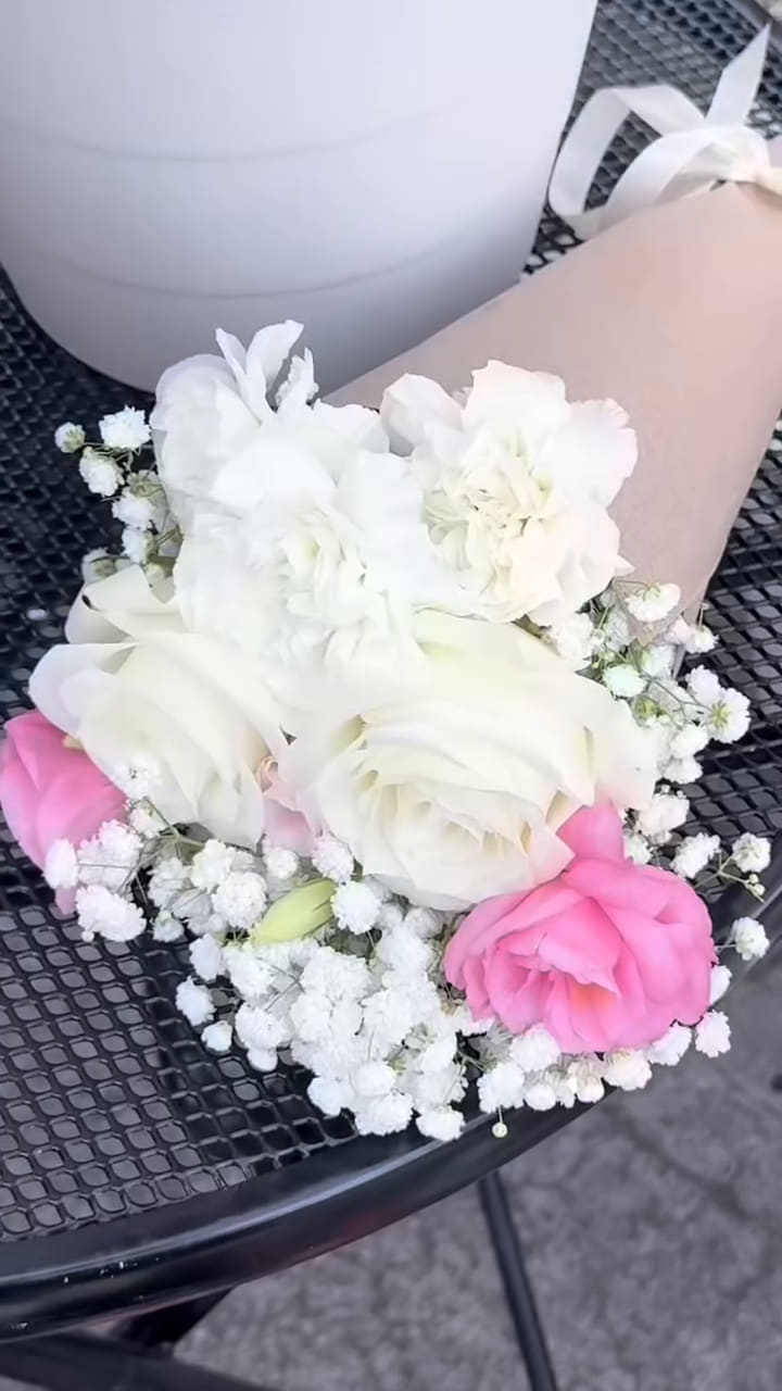 A finished white-rose cone with baby's breath resting on a café table