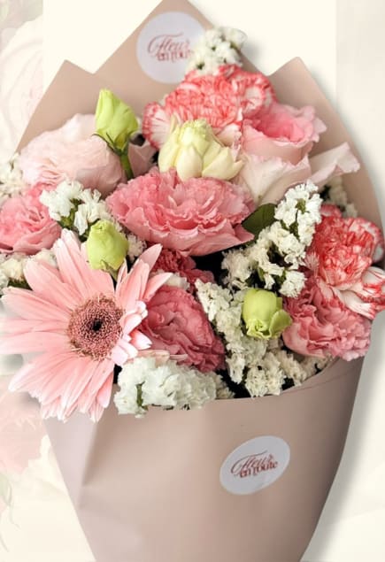 Pastel bouquet of pink carnations, lisianthus, and a pale gerbera in cream wrap