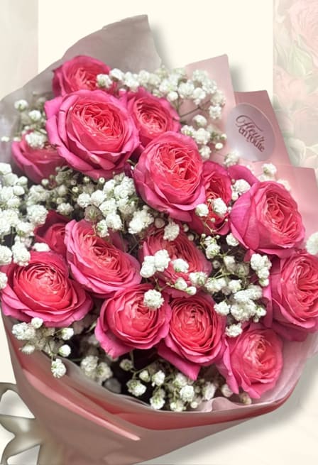 Hot-pink spray roses with baby's breath, wrapped in blush pink paper