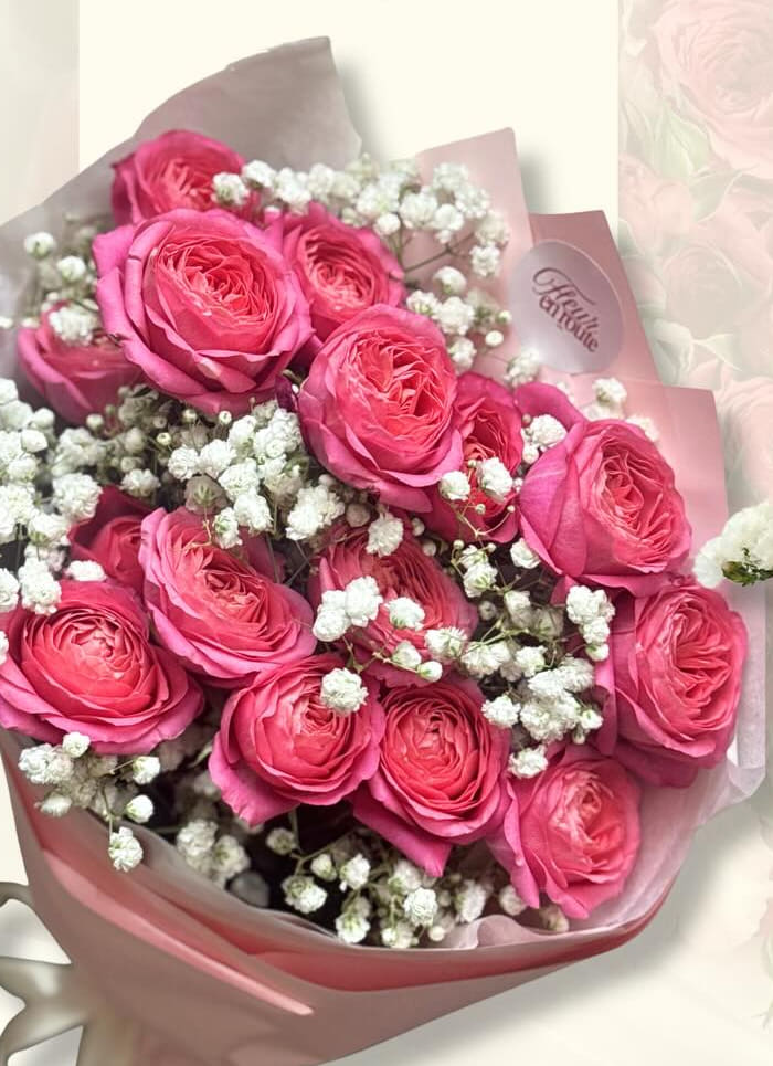 Hot-pink spray roses with baby's breath, wrapped in blush pink paper