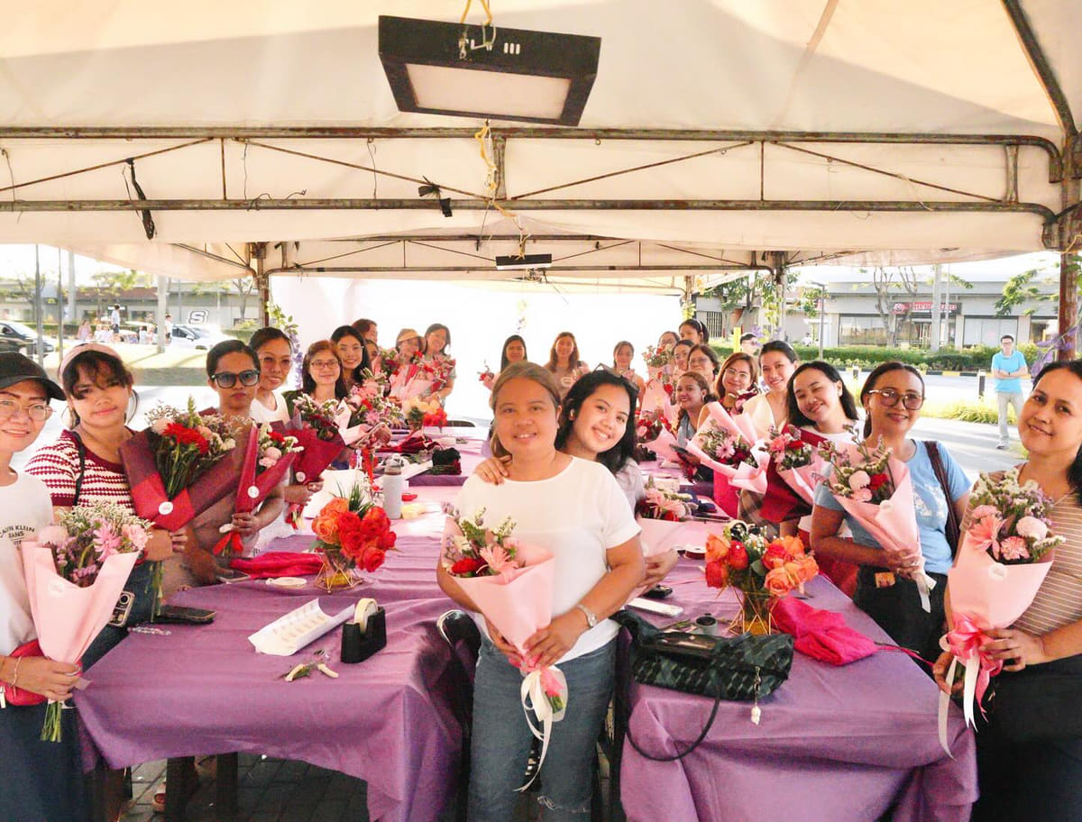 A long table of people proudly holding the bouquets they arranged themselves at The Bloom Bar